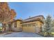 Exterior of house with stone accents and a paved driveway.Landscaped with trees at 7818 Vallagio Ln, Englewood, CO 80112