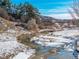 A stream runs through a snow-dusted landscape, surrounded by trees and hills at 567 Lake Gulch Rd, Castle Rock, CO 80104