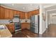 Kitchen with wood cabinets, stainless steel appliances, and dark hardwood floors at 385 N Flat Rock St, Aurora, CO 80018