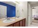 Bathroom with double vanity, blue accent wall, and view of bedroom at 385 N Flat Rock St, Aurora, CO 80018