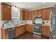 Kitchen with wood cabinets, stainless steel appliances, and dark hardwood floors at 385 N Flat Rock St, Aurora, CO 80018