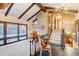 Living room with a fireplace, wood beam ceiling, large windows, and staircase at 10090 E Ohio Ave, Denver, CO 80247