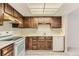 Galley kitchen with wood cabinets, white appliances, and tiled floor at 13890 E Marina Dr # 111, Aurora, CO 80014