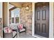 Front door with stone entryway and wicker chairs at 6251 N Malaya St, Aurora, CO 80019