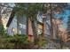 Exterior of a charming two-story home nestled in a wooded area, showcasing a deck and stone retaining wall at 4885 Silver Spruce Ln, Evergreen, CO 80439