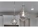 Close-up of stylish glass pendant lights above the kitchen island at 13502 E 100Th Ave, Commerce City, CO 80022
