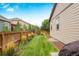 View of a grassy backyard, wooden fence and house exterior at 15373 E 113Th Pl, Commerce City, CO 80022