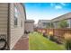 Backyard with a grassy area, wooden fence, and partial house view at 15373 E 113Th Pl, Commerce City, CO 80022