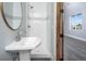 Modern bathroom with pedestal sink, tile shower, and circular mirror at 1490 Saint Andrews Dr, Broomfield, CO 80020