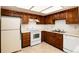 Kitchen with wood cabinets, white appliances, and a double sink at 13961 E Marina Dr # 106, Aurora, CO 80014