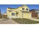 A yellow two-story house with solar panels, a white picket fence, and a two-car garage at 20937 Kelly Pl, Denver, CO 80249