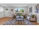 Living room with green sofa, wood floors, and geometric rug at 7946 Joan Dr, Denver, CO 80221