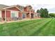Townhome exterior with lawn, showcasing its red siding at 13722 Legend Way # 101, Broomfield, CO 80023