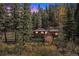 Exterior view of house nestled in trees at dusk at 28532 Shadow Mountain Dr, Conifer, CO 80433