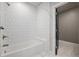 Bright bathroom with white tile, bathtub, and dark-framed door at 7285 S Titus Way, Aurora, CO 80016