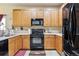 Modern kitchen featuring wood cabinets, black appliances, and a large kitchen island at 14389 E 101St Pl, Commerce City, CO 80022