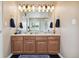 Double vanity bathroom with a large mirror and updated light fixtures at 14389 E 101St Pl, Commerce City, CO 80022