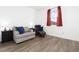 Cozy bedroom with grey couch, wood floors, and a window with red curtains at 3924 Alamosa Ct, Brighton, CO 80601