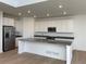 Modern kitchen featuring white cabinets, a large island, and light hardwood floors at 584 Twilight St, Erie, CO 80516