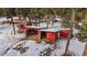 Aerial view of red outbuildings, a driveway, and a wooded area in winter at 8838 Hillview Rd, Morrison, CO 80465