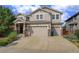 Two-story house with beige siding, a three-car garage, and landscaping at 15453 E 109Th Ave, Commerce City, CO 80022