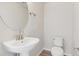 Powder room featuring a pedestal sink, toilet, and round mirror at 455 Interlocken Blvd # 102, Broomfield, CO 80021