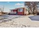 Brick ranch home with a covered porch and snowy lawn at 2200 W Moffat Pl, Denver, CO 80221