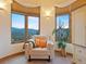 Light beige armchair in a sitting area with mountain views from large windows at 29115 Summit Ranch Dr, Golden, CO 80401