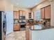 Kitchen with stainless steel appliances, granite countertops, wood cabinetry, and tile flooring at 10916 Towerbridge Rd, Highlands Ranch, CO 80130