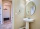 Half bathroom with a pedestal sink and a round mirror at 10916 Towerbridge Rd, Highlands Ranch, CO 80130