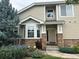 Tan two-story home with stone accents, landscaping, and a two-car garage at 7482 W Saratoga Pl, Littleton, CO 80123