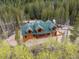 Aerial view of log cabin nestled in a mountain forest setting at 733 Rainbow Rd, Idaho Springs, CO 80452