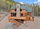 Aerial view of a log cabin home with green roof in wooded area at 733 Rainbow Rd, Idaho Springs, CO 80452