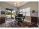 Music room with grand piano, hardwood floors, and access to backyard patio at 5069 Castle Pines S Dr, Castle Rock, CO 80108