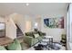 Open-concept living room with green sofas, a view of the kitchen, and a staircase at 6233 N Liverpool St, Aurora, CO 80019