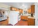 Kitchen with light wood cabinets, white appliances, and brick tile floor at 1432 Xanthia St, Denver, CO 80220