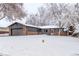 Brick ranch home with attached garage, freshly painted in gray and surrounded by snowy landscape at 185 W 9Th Ave, Broomfield, CO 80020