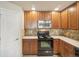 Compact kitchen with wood cabinetry, black appliances, and tiled backsplash at 1170 Olympia Ave # I, Longmont, CO 80504