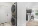 Modern laundry room with stacked washer and dryer, and a view into the kitchen at 7214 Aspen Brook Ave, Frederick, CO 80530