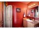 Bathroom with red walls, wood vanity, and a unique door at 11566 Coal Creek Heights Dr, Golden, CO 80403