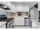 Bright kitchen with white cabinets, stainless steel appliances, and a view into the living area at 8140 S Fillmore Cir, Centennial, CO 80122