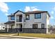 Modern two-story home with a balcony, stone accents, and a landscaped front yard at 2460 S Clay St, Denver, CO 80219