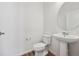 Powder room with a pedestal sink, round mirror, and wood-look flooring at 6940 Merseyside Ln, Castle Pines, CO 80108