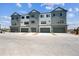 Modern townhomes with gray and white siding, attached garages, and paved driveways at 6940 Merseyside Ln, Castle Pines, CO 80108