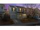 Two-story house with gray siding, attached garage, and a tree in the front yard at dusk at 10706 Butte Dr, Longmont, CO 80504