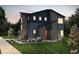 Two-story modern home with dark siding, landscaping, and a red front door at 23950 E 41St Ave, Aurora, CO 80019