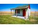 Charming storage shed with a porch and red door at 6751 S County Road 129, Bennett, CO 80102