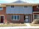 Brick and gray two-story townhome with a security door and landscaping at 1165 Milky Way, Thornton, CO 80260
