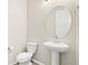 Small powder room with pedestal sink, toilet and round mirror at 2125 E 150Th Pl, Thornton, CO 80602