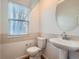 Clean bathroom with pedestal sink, toilet, and window with blinds at 8142 E Vassar Dr, Denver, CO 80231